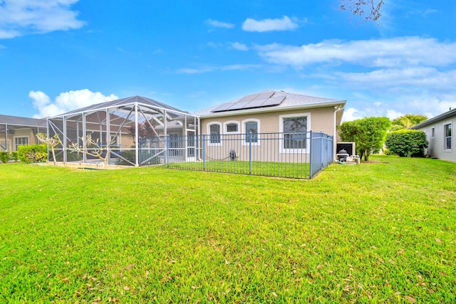 rear view of house featuring a lawn and solar panels