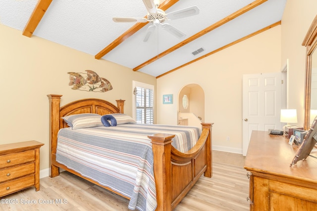 bedroom featuring light wood-type flooring, vaulted ceiling with beams, and a textured ceiling