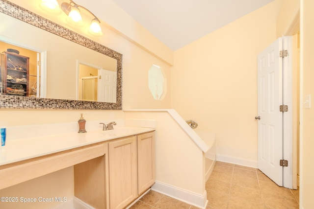 bathroom with a tub, vanity, and tile patterned flooring