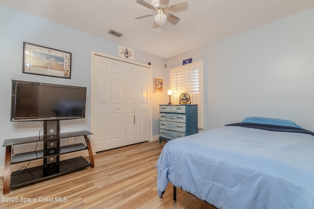 bedroom featuring light wood-type flooring, a closet, ceiling fan, and a textured ceiling