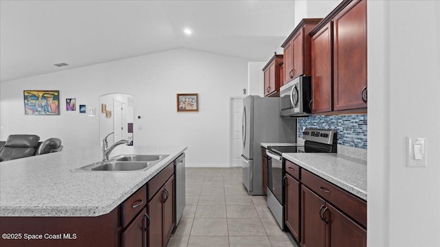 kitchen featuring sink, appliances with stainless steel finishes, a kitchen island with sink, light tile patterned flooring, and vaulted ceiling