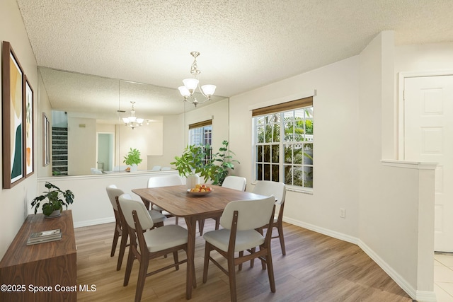 dining room featuring a chandelier, light hardwood / wood-style flooring, and a textured ceiling