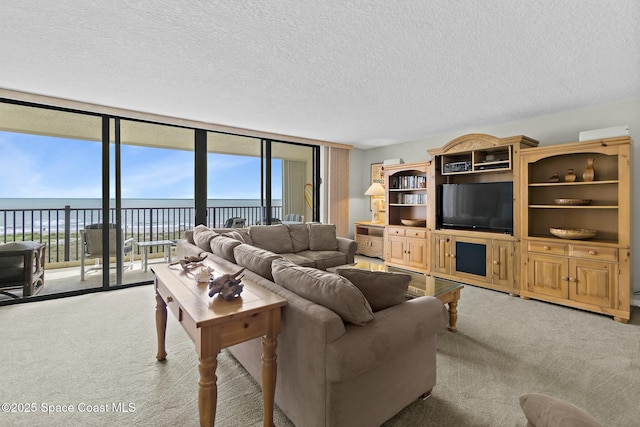 carpeted living room featuring a textured ceiling, floor to ceiling windows, and a water view