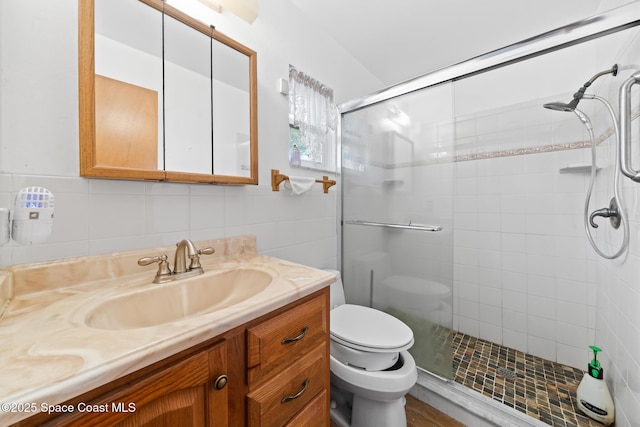 bathroom featuring tile walls, vanity, a shower with shower door, and toilet