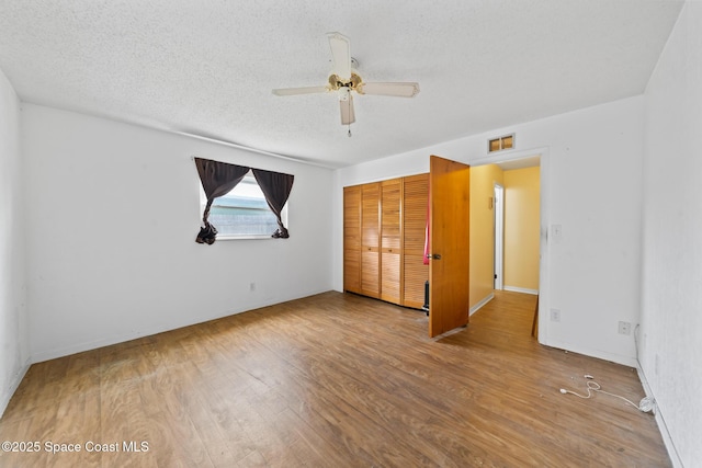 unfurnished bedroom with ceiling fan, hardwood / wood-style floors, a textured ceiling, and a closet