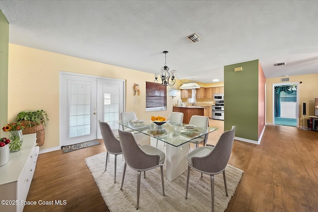 dining area featuring hardwood / wood-style flooring, an inviting chandelier, and a textured ceiling