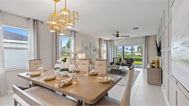 dining space with light tile patterned floors, a wealth of natural light, ceiling fan with notable chandelier, and visible vents