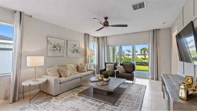 living area with light tile patterned floors, ceiling fan, visible vents, and baseboards