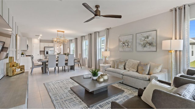 living area featuring light tile patterned floors and ceiling fan with notable chandelier