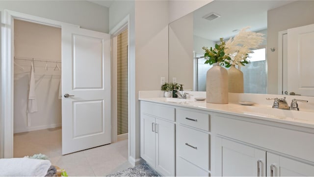 full bathroom featuring double vanity, visible vents, a sink, and tile patterned floors