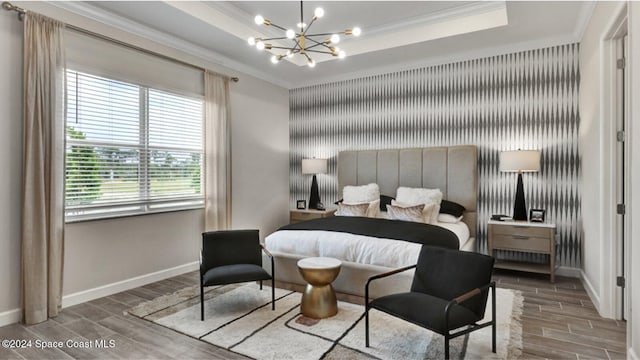 bedroom with an inviting chandelier, ornamental molding, and a tray ceiling