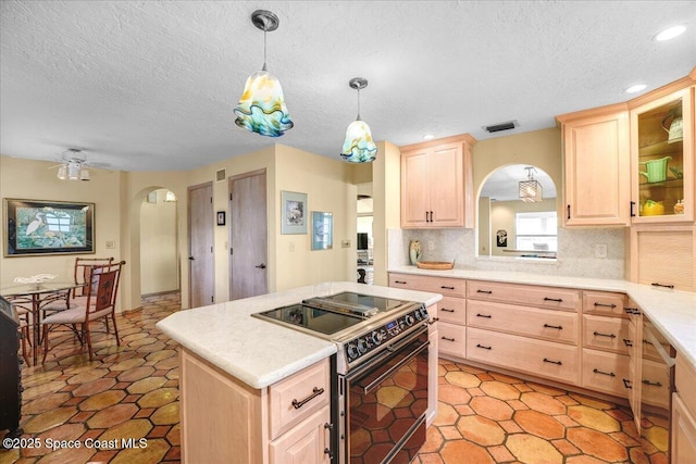 kitchen featuring electric stove, hanging light fixtures, a center island, tasteful backsplash, and light brown cabinets