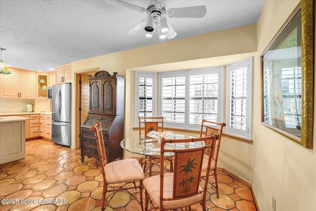 tiled dining area featuring ceiling fan and a textured ceiling