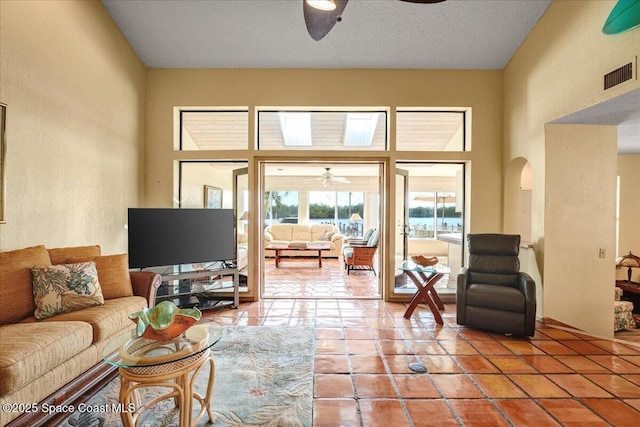 living room featuring tile patterned floors, ceiling fan, and a high ceiling