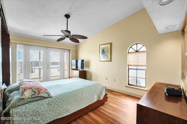 bedroom with light hardwood / wood-style floors, vaulted ceiling, multiple windows, and access to outside