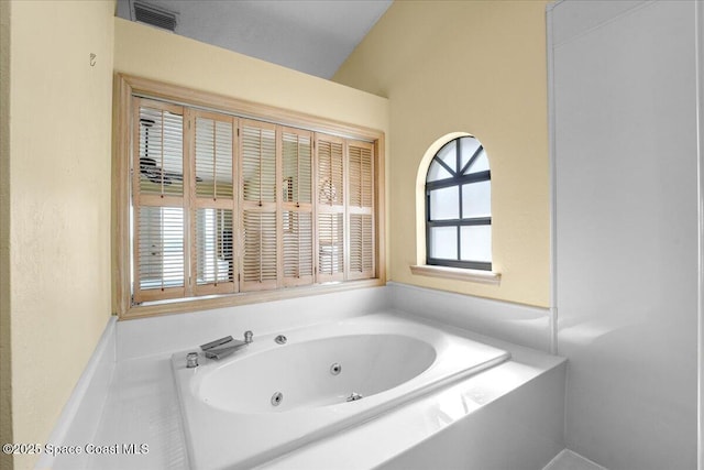 bathroom with lofted ceiling and a bathtub