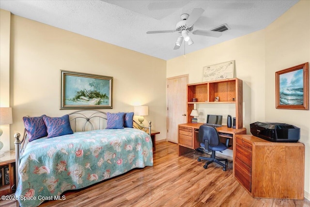 bedroom featuring ceiling fan, light hardwood / wood-style floors, and a textured ceiling