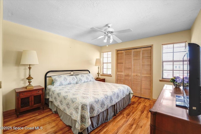 bedroom with ceiling fan, hardwood / wood-style floors, a closet, and a textured ceiling