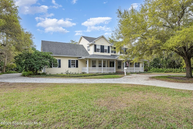 view of front facade featuring covered porch, driveway, a front lawn, and roof with shingles