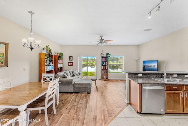 kitchen featuring sink, hanging light fixtures, light wood-type flooring, dark stone countertops, and dishwasher