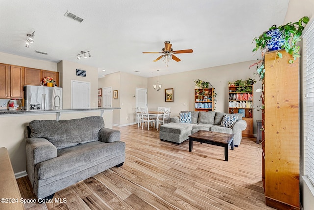 living room featuring a textured ceiling, track lighting, ceiling fan, and light wood-type flooring