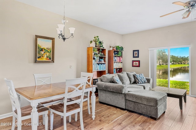 dining area featuring a water view, ceiling fan with notable chandelier, and light hardwood / wood-style flooring