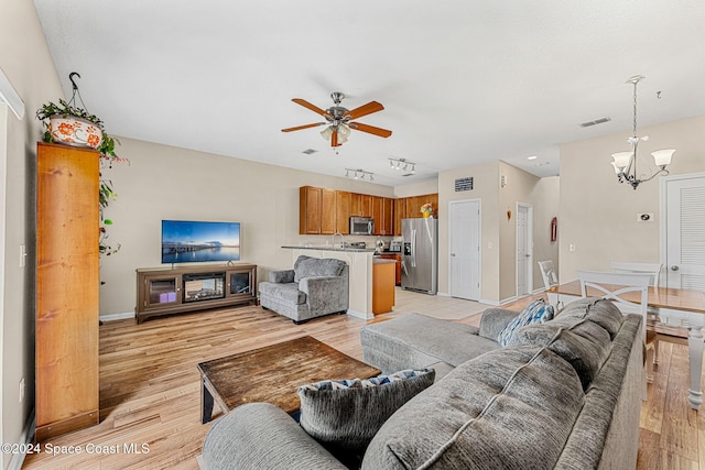 living room with ceiling fan with notable chandelier, light hardwood / wood-style floors, and rail lighting