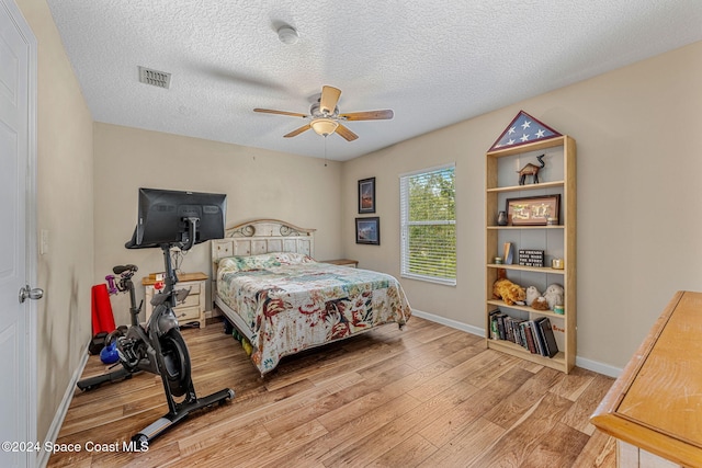 bedroom with ceiling fan, light hardwood / wood-style flooring, and a textured ceiling