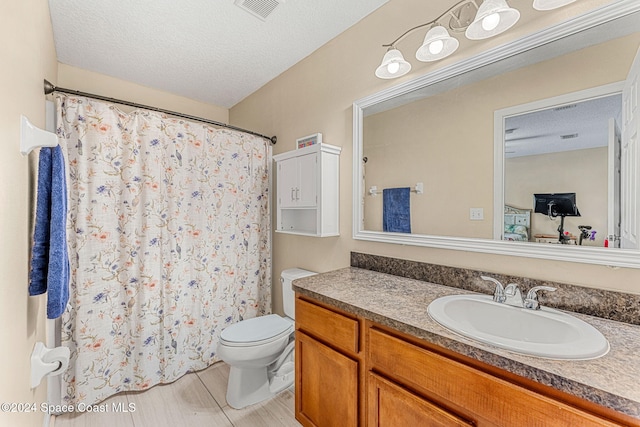 bathroom featuring vanity, toilet, and a textured ceiling