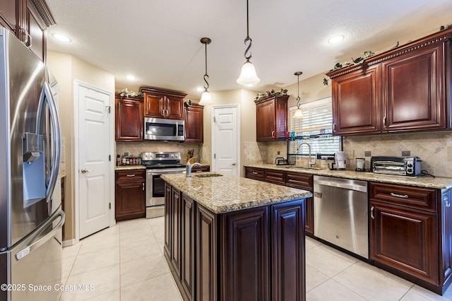 kitchen featuring sink, light tile patterned floors, stainless steel appliances, a kitchen island, and decorative light fixtures