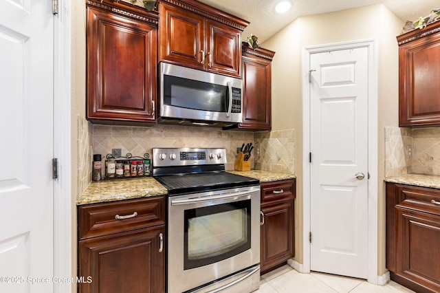 kitchen featuring stainless steel appliances, light tile patterned floors, backsplash, and light stone counters