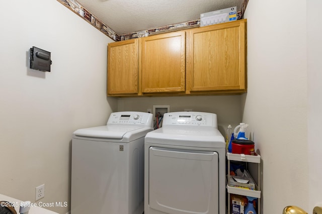 laundry room featuring cabinets, washer and dryer, and a textured ceiling