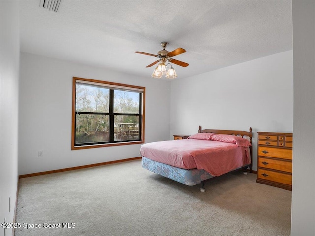 carpeted bedroom with ceiling fan and a textured ceiling