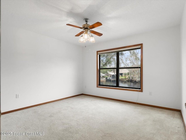 unfurnished room featuring ceiling fan, a water view, light carpet, and a textured ceiling