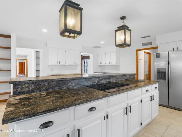 kitchen with stainless steel fridge, a center island, black electric stovetop, white cabinets, and decorative light fixtures