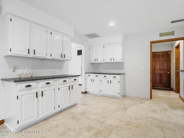 kitchen featuring white cabinetry and brick wall