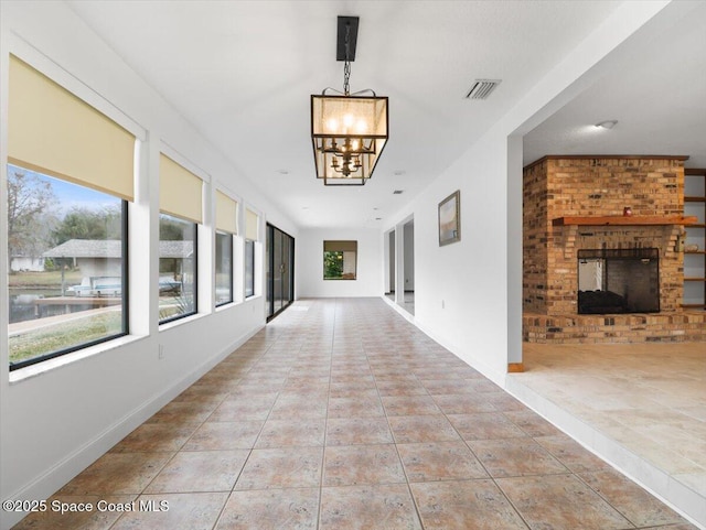 hallway with light tile patterned flooring and a chandelier