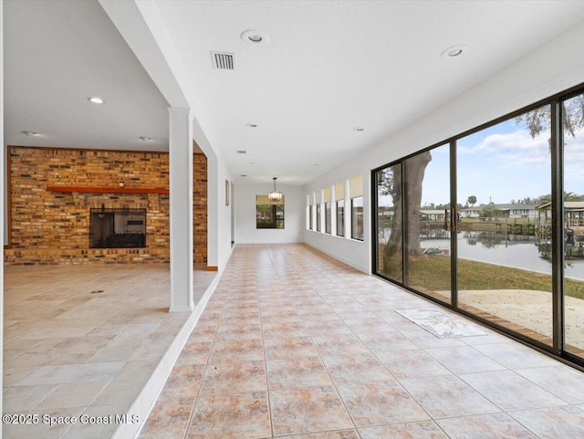 unfurnished sunroom with a water view and a brick fireplace