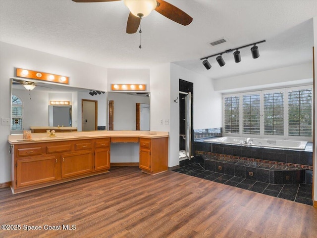 bathroom with tiled tub, vanity, hardwood / wood-style floors, and a textured ceiling