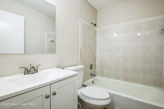 full bathroom featuring tiled shower / bath, vanity, and toilet