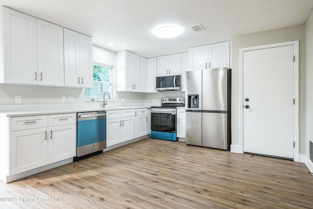 kitchen featuring stainless steel appliances, light hardwood / wood-style floors, and white cabinets