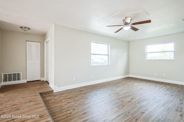 unfurnished room featuring ceiling fan, hardwood / wood-style floors, a textured ceiling, and a wealth of natural light