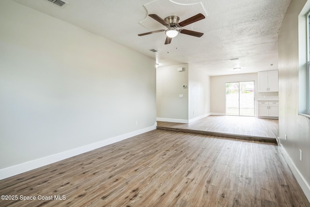 empty room with ceiling fan, light hardwood / wood-style flooring, and a textured ceiling