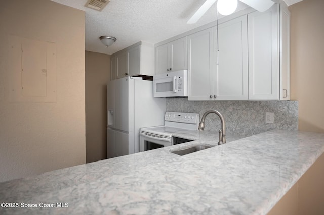 kitchen with white cabinetry, sink, decorative backsplash, kitchen peninsula, and white appliances