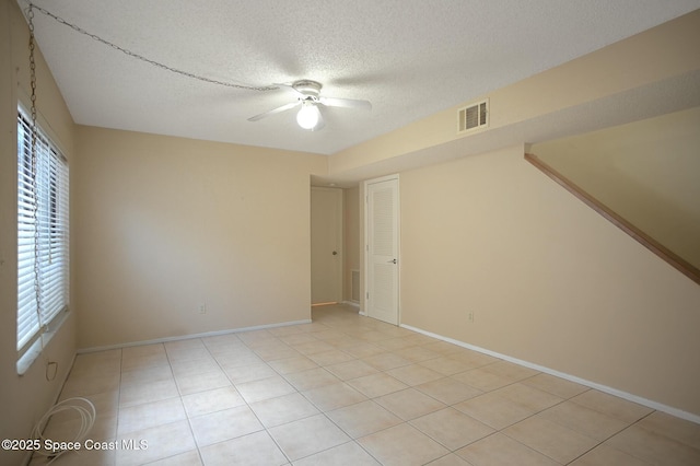 tiled spare room with a textured ceiling and ceiling fan