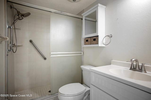 bathroom featuring a shower with door, vanity, and toilet