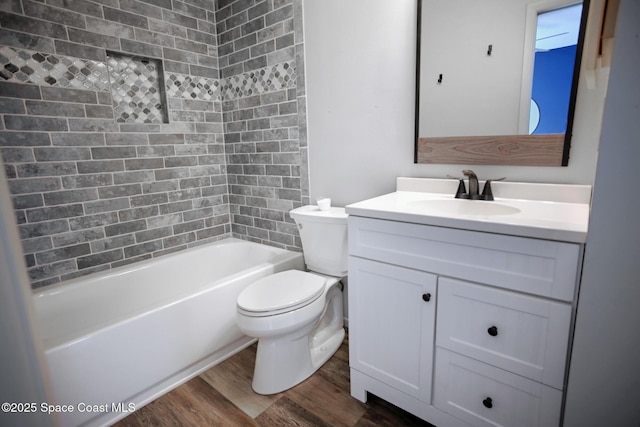 full bathroom featuring vanity, hardwood / wood-style flooring, tiled shower / bath combo, and toilet