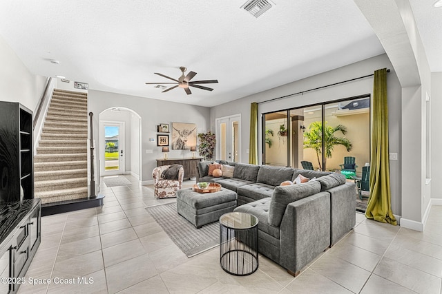 living room with ceiling fan, light tile patterned floors, and a textured ceiling