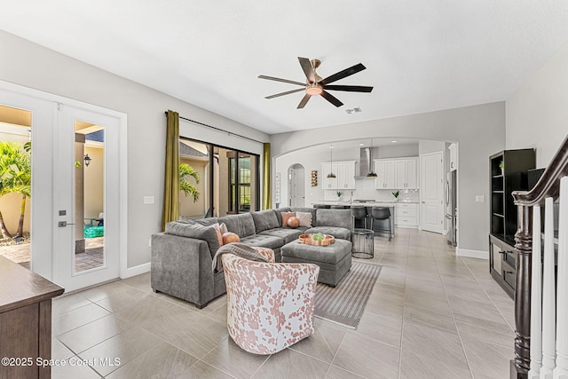 tiled living room with french doors and ceiling fan