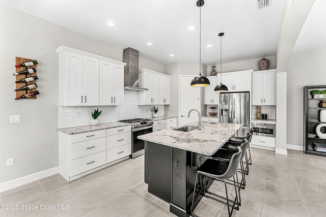 kitchen featuring sink, white cabinetry, stainless steel appliances, a center island with sink, and wall chimney exhaust hood